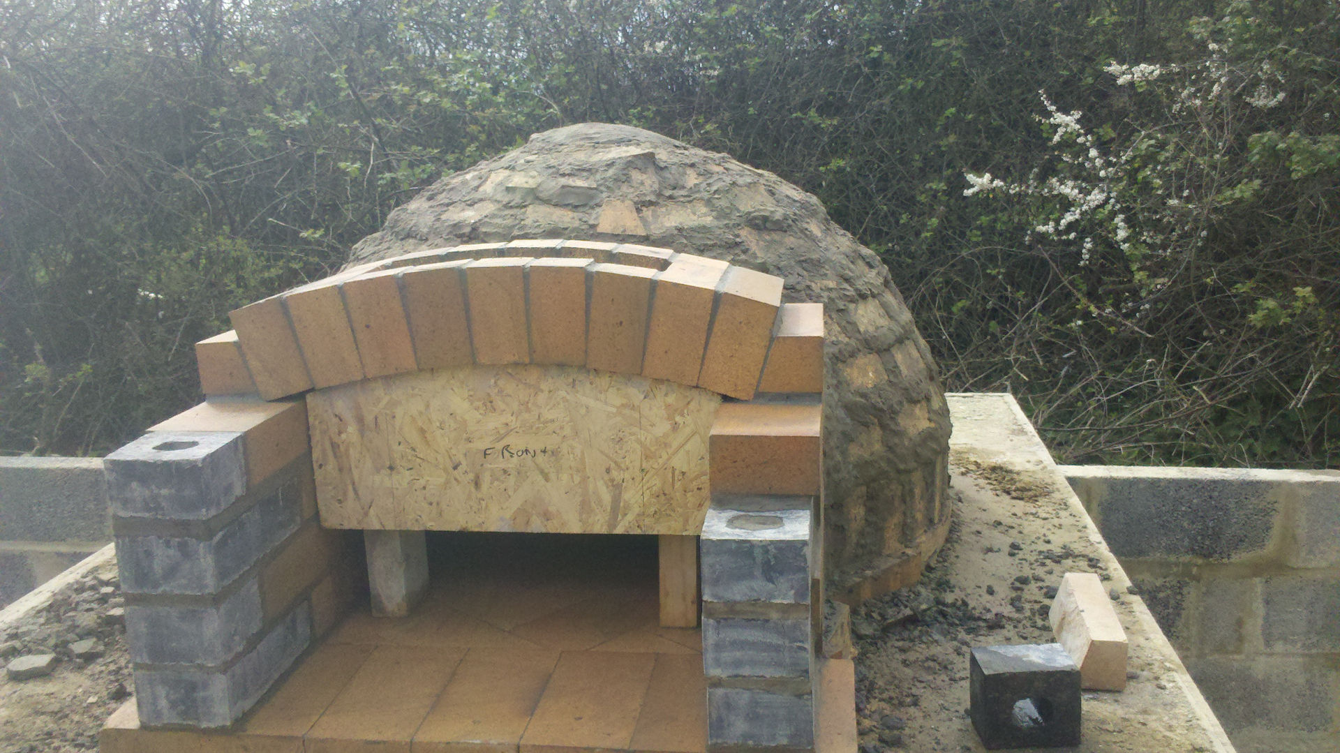 Wood-fired pizza oven archway over porch being installed